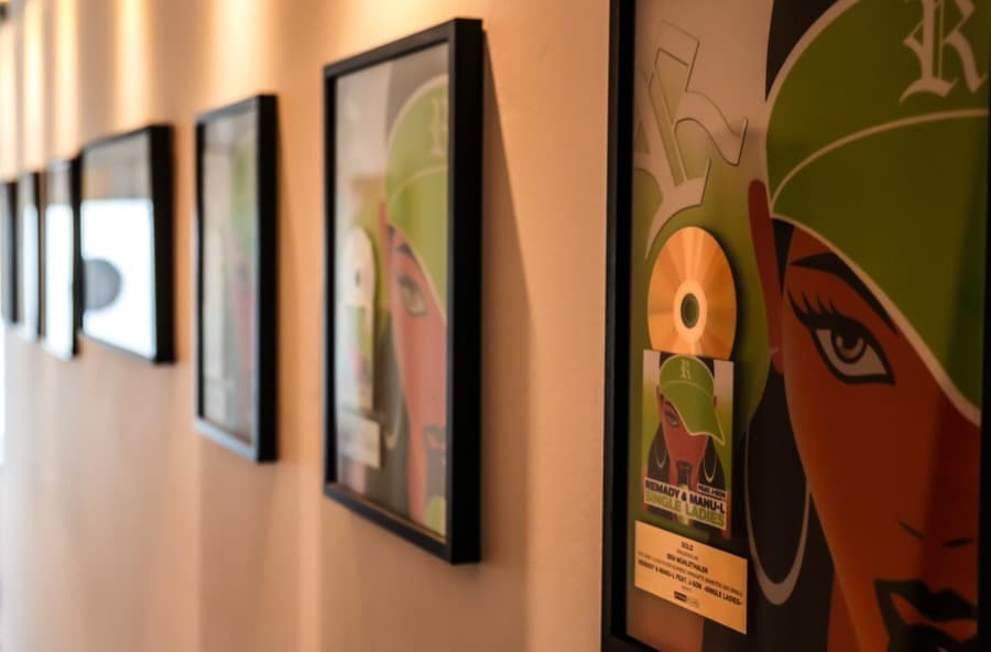 Framed gold and platinum awards along a B-Note studio corridor